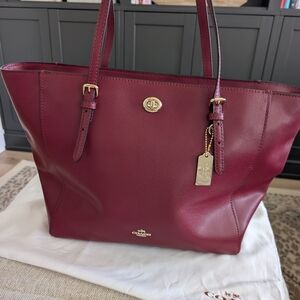 Coach Turnlock Tote bag in crossgrain leather and an oxblood or burgundy color. 